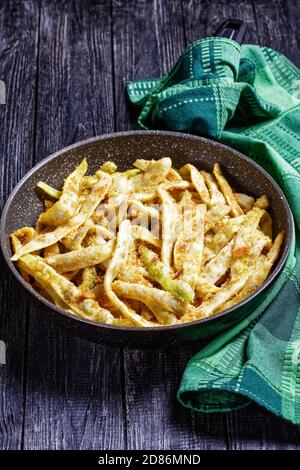 Piatto vegetariano: Fagioli di cera d'oro francesi con aglio e prezzemolo ricoperti di pangrattato e fritti su una padella su fondo di legno scuro, vista dall'alto, Foto Stock