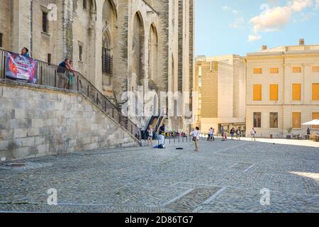 Un turista prende una foto come lei gode di una street performer suonare il sassofono nella parte anteriore del Palazzo dei Papi di Avignone Francia Foto Stock