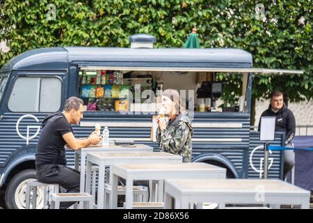 Londra, Regno Unito, 28 luglio 2019. Ragazzo e ragazza mangiano il gelato seduto ad un tavolo vicino al furgone che vende il gelato Foto Stock