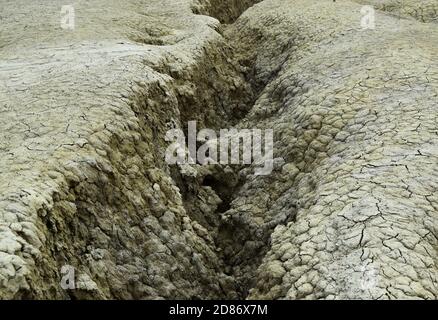 Canale dell'acqua ondulato in consistenza di suolo asciutto. I Vulcani di fango sono una riserva geologica e botanica a Paclele Mari vicino a Buzau, Romania. Piccolo volc Foto Stock