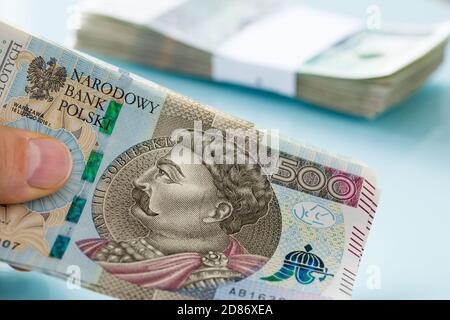 Una grande quantità di banconote polacche da cinquecento zloty nella mano in background un pacchetto di denaro fissato con un nastro di banco Foto Stock