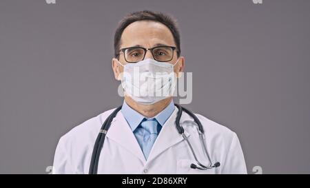 Attraente medico toglie la maschera protettiva contro covid-19 , sorrisi felici Foto Stock