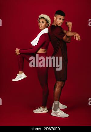 Coppia afroamericana che fa esercizio fisico insieme. coppia di fitness in piedi con la schiena in piedi l'uno contro l'altro su sfondo marrone. Foto Stock