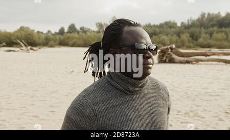 Ritratto di un giovane bell'uomo nero afroamericano sulla spiaggia di sabbia in inverno. Foto di alta qualità Foto Stock