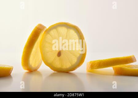 Dettaglio di diversi tagli di limone su tavola bianca e sfondo isolato. Vista frontale. Composizione orizzontale. Foto Stock