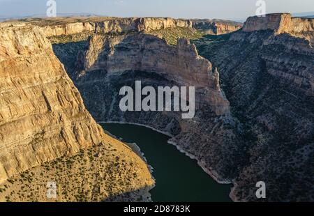 Un'ansa fluviale si snoda tra imponenti pareti di canyon stratificate color calcare, con un fiume verde in basso nella Bighorn Canyon National Recreation Area. Foto Stock
