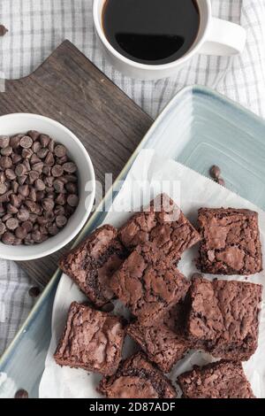 Brownie di cioccolato mastodoroso su piatto blu con tazza fresca di caffè Foto Stock