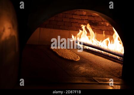 Cucina turca, pane pita in mattoni di pietra forno a fiamma naturale su tavola di legno, pane caldo fresco cotto, spazio copia. Immagine concettuale di panetteria o panetteria. Foto Stock