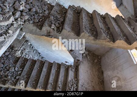 Scalinata in cemento intemperie schiacciata all'interno del pavimento abbandonato rovinato dell'edificio sovietico. Città incompiuta, rovinata intemperie casa a più piani Foto Stock