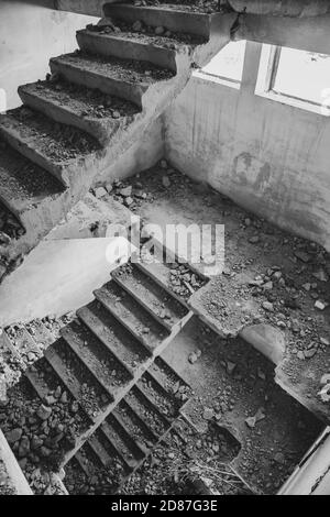 Scalinata in cemento bianco e nero intemperie all'interno di un pavimento abbandonato in rovina dell'edificio sovietico. Città incompiuta, rovinata intemperie casa a più piani Foto Stock