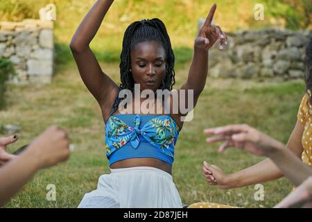 Donna nera sorridente che si diverte con un gruppo di amici un parco Foto Stock