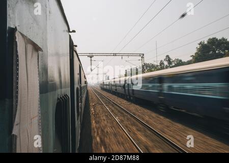 Treno espresso ordinario in un viaggio da Nuova Delhi ad Agra passando da un altro treno nella direzione opposta. Foto Stock