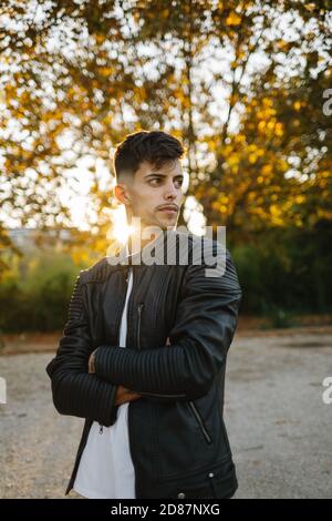 bel ragazzo con giacca in pelle che si posa in un tramonto d'autunno Foto Stock