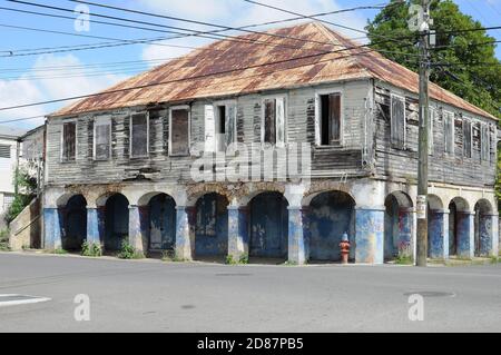 Una vecchia casa abbandonata con un tetto arrugginito, pareti in legno dilatate e colonne di sostegno con archi.casa abbandonata a un bivio. Foto Stock