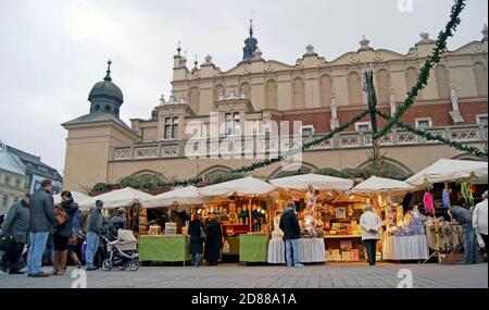 La gente frequenta un mercato turistico fuori dalla sala dei tessuti nella più grande piazza medievale d'Europa a Cracovia, Polonia. Foto Stock