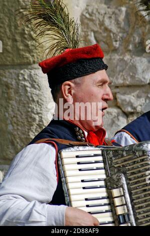 Il vecchio polacco canta e suona la fisarmonica in una strada nella città vecchia di Cracovia, Polonia, il 13 marzo 2010. Foto Stock