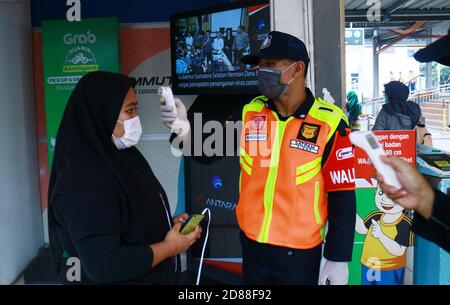 Depok, Indonesia - 18 marzo 2020: Gli agenti di sicurezza controllano la temperatura corporea dei passeggeri all'ingresso della stazione ferroviaria di Depok per prevenire il Foto Stock