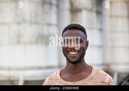Giovane uomo nero sorridente alla macchina fotografica. Verticale. Scatto medio. Foto Stock