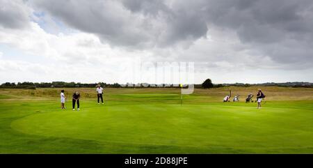 QUINEVILLE, FRANCIA - SETTEMBRE CIRCA, 2020. Tre uomini e donne maturi che giocano a golf in un campo da golf professionale. Su erba verde grande, cercando di mettere t Foto Stock