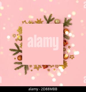Mockup di carta rosa quadrata con cornice fatta di decorazioni natalizie e rami di abete. Composizione lucida con bokeh dorato. Foto Stock