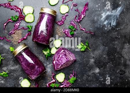 Smoothies disintossicazione sano e utile o succo di cavolo rosso, cetrioli con semi di chia in bottiglie di vetro su uno sfondo grigio, vista dall'alto Foto Stock