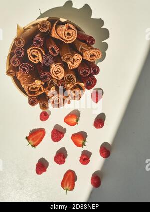 Bicchiere di pastelli fatti a mano con diversi sapori e fragole su un tavolo bianco. Foto Stock