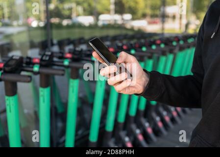 Uomo che usa l'app per il telefono cellulare per noleggiare un calciatore elettrico Foto Stock