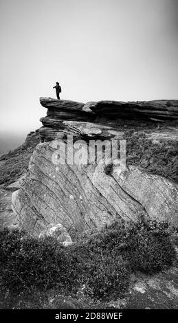 Una vista di Bamford Edge in una mattinata grigia nebbiosa con un fotografo in piedi vicino al confine .Peak distretto National Park, Derbyshire, Inghilterra, Regno Unito Foto Stock