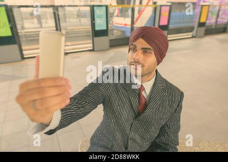 Giovane bell'uomo d'affari indiano Sikh che indossa il turbante mentre esplorando il città Foto Stock