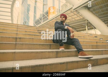 Giovane bell'uomo d'affari indiano Sikh che indossa il turbante mentre esplorando il città Foto Stock
