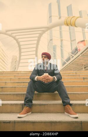 Giovane bell'uomo d'affari indiano Sikh che indossa il turbante mentre esplorando il città Foto Stock