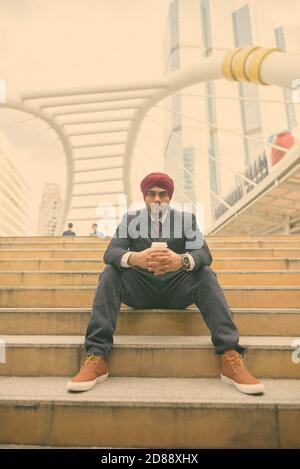 Giovane bell'uomo d'affari indiano Sikh che indossa il turbante mentre esplorando il città Foto Stock