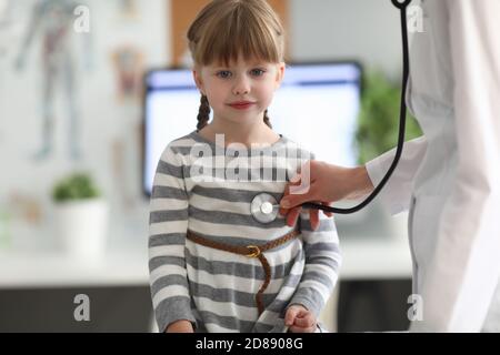 Il pediatra ascolta il cuore con stetoscopio alla bambina dentro l'ufficio della clinica Foto Stock