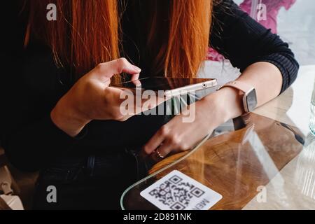 Donna che scannerizza il codice qr del codice a barre in un ristorante o in un bar Foto Stock