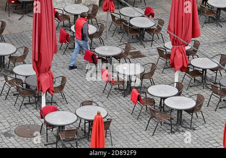 Monaco, Germania. 28 Ott 2020. Un uomo cammina tra le file vuote di tavoli in un caffè di strada nella zona pedonale. Credit: Peter Kneffel/dpa/Alamy Live News Foto Stock