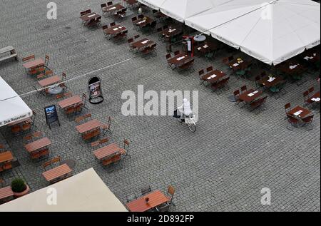 Monaco, Germania. 28 Ott 2020. Una donna in bicicletta corre tra ristoranti vuoti nella zona pedonale. Credit: Peter Kneffel/dpa/Alamy Live News Foto Stock