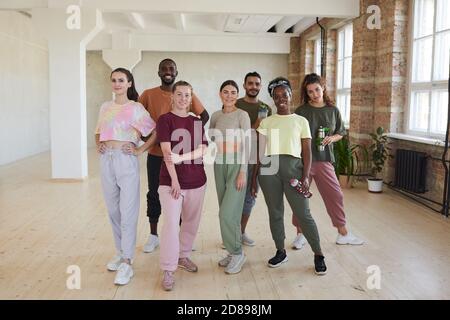 Ritratto di gruppo multietnico di ballerini sorridenti alla macchina fotografica mentre in piedi in studio di danza Foto Stock