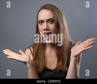 Foto di donna perplessa con labbra viola su sfondo grigio Foto Stock