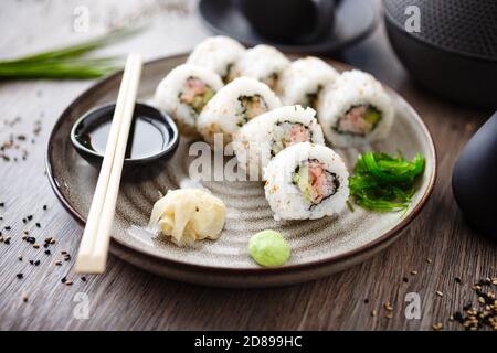 Sushi maki Rolls California con granchio, cetriolo e avocado su un piatto con chopsticks, salsa di soia, wasabi e zenzero. Tradizionale pesce giapponese Foto Stock