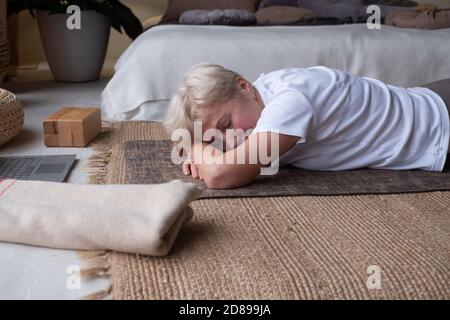 Donna anziana si rilassa in yoga asana Makarasana o coccodrillo posa Foto Stock