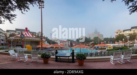 La nebbia mattutina oscura parzialmente il Walt Disney World Swan Hotel dall'altra parte della piscina del Disney's Boardwalk Inn, Florida Foto Stock