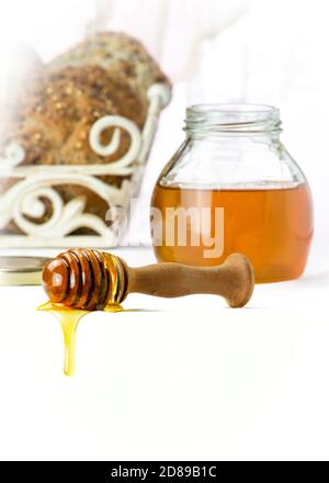 sgocciolando il miele da un cucchiaia con un vaso di miele nel backgound verticale, sparato per lo spazio di copia alla base delle immagini Foto Stock