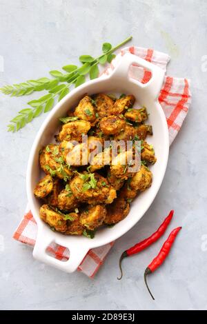 Mescolare le radici di taro fritte. Arbi ki sabji, Taro radici masala curry. Arbi Masala. Guarnito con coriandolo, peperoncino rosso e foglie di curry. Copia spazio. Foto Stock