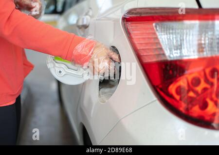 Rifornimento, riempimento del serbatoio di un'auto. Mano di donna che chiude la porta di deposito dell'auto dopo aver riempito il serbatoio con benzina Foto Stock