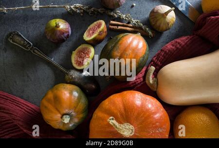 Foto dall'alto di butternut, zucca gemma, zucca, nocciolo dorato, carota, fichi, patate dolci, cipolla, arance e prezzemolo. Concetto di alimentazione sana. Foto Stock