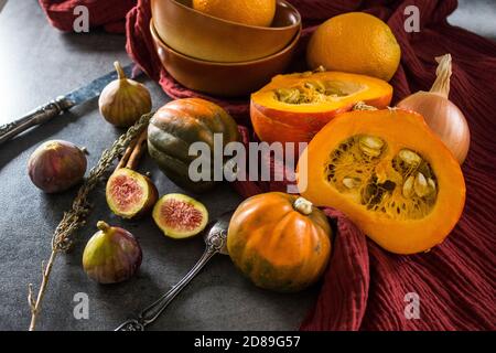 Foto dall'alto di butternut, zucca gemma, zucca, nocciolo dorato, carota, fichi, patate dolci, cipolla, arance e prezzemolo. Concetto di alimentazione sana. Foto Stock