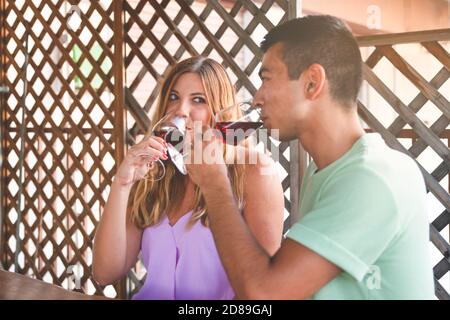 Buon momento con una coppia di razza mista bere vino e Laughing. Concetto di bere in coppia Foto Stock