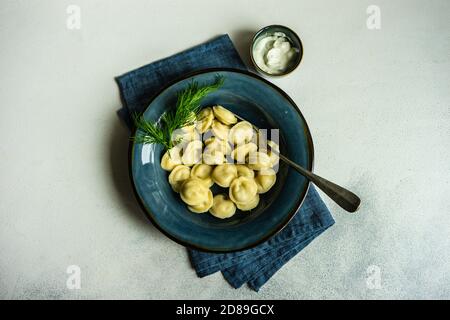 Vista dall'alto di ciotola di gnocchi pelmeni tradizionali russi con panna acida e aneto Foto Stock