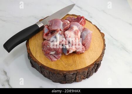 Carni fresche di capra cruda o pezzi di montone o di agnello. Preparazione per il curry di montone indiano. Spezie sullo sfondo come bastoncini di cannella, peperoncino rosso in polvere, Foto Stock