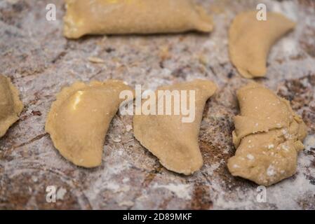 Gnocchi con formaggio di cottage nel processo di preparazione e preparazione per la cottura. Piatti fatti in casa, cucina polacca. Impasto crudo sul tavolo. Foto Stock